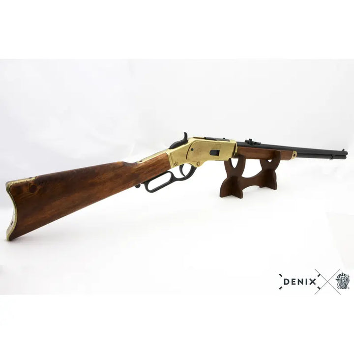 Denix Winchester 1873 replika rifle i gull på stativ, skrått forfra